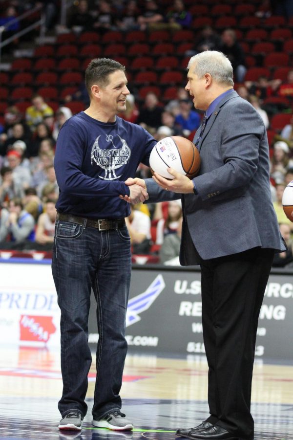 Kevin Lux, father of Nate (X15), Gabe (X18), and Jack (X21),  receives the Fan of the Game award and a commemorating basketball at the Wells Fargo Arena before the state quarterfinal game against Marion. Camryn McPherson Photo. 
