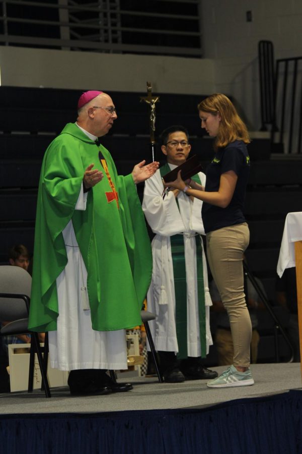Senior Anna Garbe holds the lectionary for Archbishop Jackels as he opens the Back-to-School Mass with prayer.